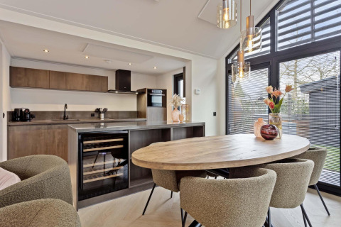 Cocina de lodge moderna con mesa de madera, cuatro sillas tapizadas, grandes ventanales y luz natural.