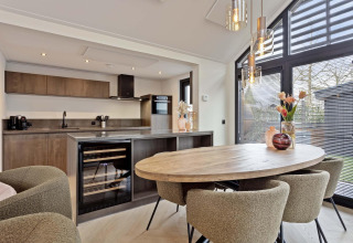 Cocina de lodge moderna con mesa de madera, cuatro sillas tapizadas, grandes ventanales y luz natural.