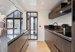 Cocina moderna en lodge con muebles oscuros, puerta de cristal y suelo de madera clara y elegante.