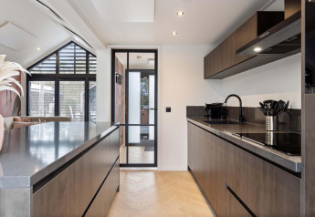 Cocina moderna en lodge con muebles oscuros, puerta de cristal y suelo de madera clara y elegante.