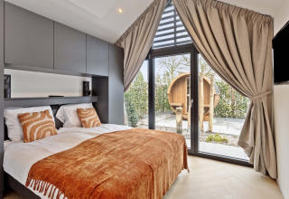 Dormitorio moderno en Lodge Royal Eco 6 personen, Résidence Lage Vuursche, con vista a sauna y grandes ventanales.