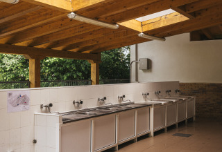 Waschbereich im Freien mit mehreren Edelstahlbecken und Holzdach, Wecamp San Sebastián, Baskenland.