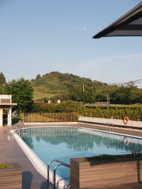 Buitenzwembad bij Wecamp San Sebastián vakantiepark met uitzicht op heuvels in Baskenland, Spanje.