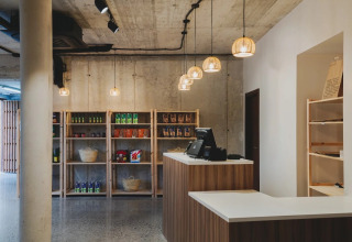 Modern reception and shop area with wooden shelves at Wecamp San Sebastián holiday park, Basque Country, Spain.
