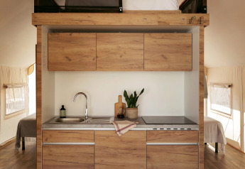 Cucina moderna con letto soppalcato nella tenda safari Glamping Family Plus al Wecamp San Sebastián, Spagna.