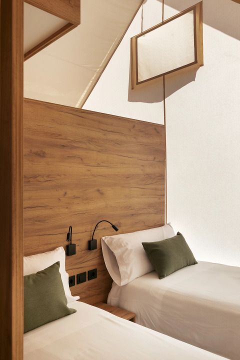Interior de una tienda safari Glamping Family Plus con dos camas en Wecamp San Sebastián, España, decoración moderna.