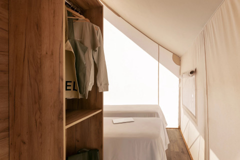 Interior de una tienda safari, Glamping Family Plus en Wecamp San Sebastián, con camas y armario.