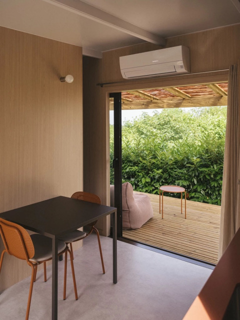 Interior moderno de cabaña con comedor y terraza exterior en Mobile home «Couple Plus» en Wecamp San Sebastián, España.