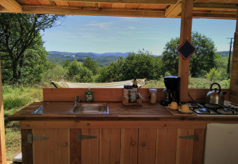 Cuisine extérieure du Bell XL family tent au camping Junora en France, avec vue sur collines et verdure.