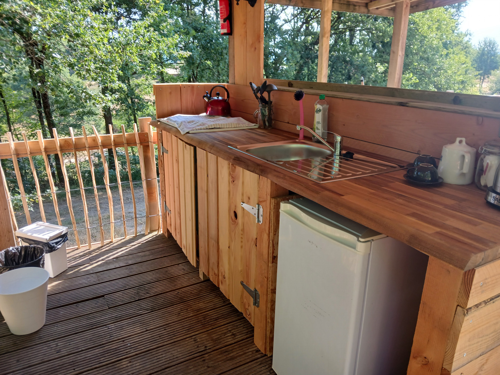 Buitenkeuken van hout met gootsteen, mini-koelkast en boszicht bij Bell tent lodge op Camping Junora.