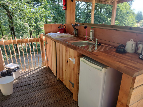Holzküche im Freien mit Waschbecken, Minikühlschrank und Waldblick im Bell Tent am Campingplatz Junora.