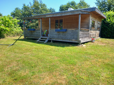 Self-sufficient, luxury eco-chalet lodge with wooden exterior and porch surrounded by greenery.