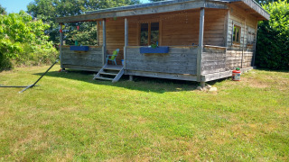 En selvforsynende, luksuriøs øko-chalet med træfacade og terrasse omgivet af grøn natur.