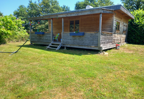 Eco-chalet di lusso autosufficiente con facciata in legno e veranda, immerso nel verde.