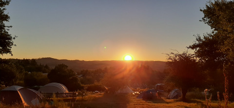 Sunrise at Bell tent «6M» at Campsite Junora in France, showing tents and a scenic natural landscape.