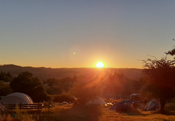 Lever de soleil sur la Bell tent «6M» au Camping Junora en France, avec tentes et paysage naturel.