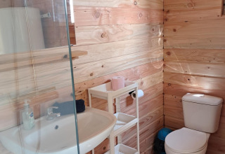 Badkamer met houten wanden, wastafel, wc en rek in de Sybley Apex tent op Campsite Junora, Frankrijk.