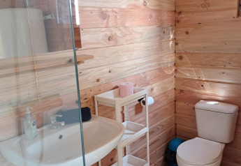 Bagno con pareti in legno, lavabo, wc e scaffale presso Sybley Apex tent al Campeggio Junora, Francia.