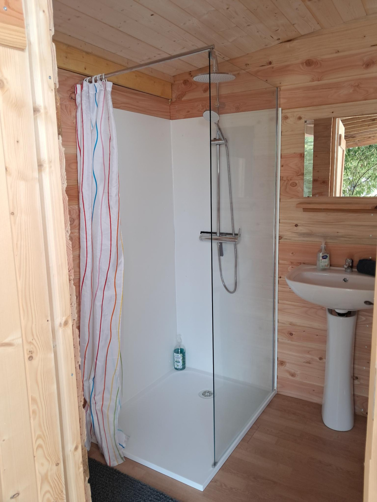 Badkamer met douche en wastafel in een houten cabine van de Sibley Apex tent op Campsite Junora, Frankrijk.