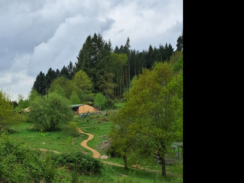 Afbeelding van Bell XL familietent bij Campsite Junora in Frankrijk, omringd door groene bomen en wolken.