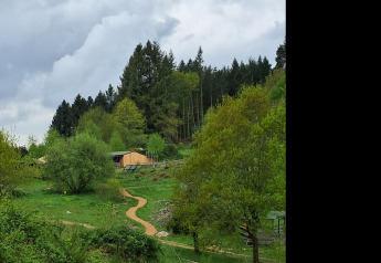 Photo de la tente familiale Bell XL au camping Junora en France, entourée d’arbres verts et de nuages.