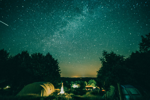 Nachtfoto van een sterrenhemel boven Sybley Apex-tent op Campsite Junora in Frankrijk, met bomen.
