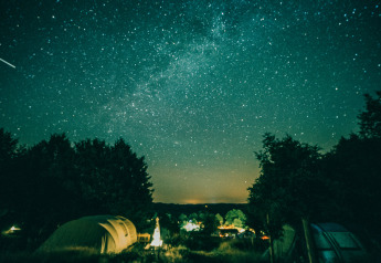 Vista notturna del cielo stellato sopra la tenda Sybley Apex al Campeggio Junora, Francia, con alberi.