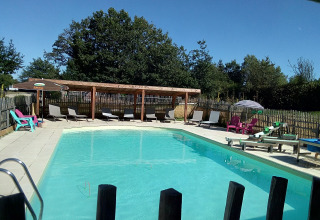 Outdoor pool with lounge chairs at Lodge 'Avignon' in Campsite Junora, France, surrounded by greenery.