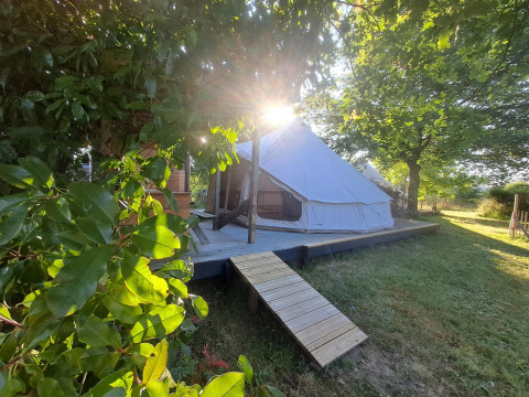 Tenda Sybley Apex illuminata dal sole al Campeggio Junora in Francia, circondata da alberi e prato verde.