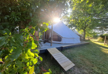 Tenda Sybley Apex illuminata dal sole al Campeggio Junora in Francia, circondata da alberi e prato verde.