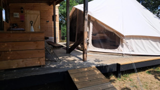 Vue extérieure d'une tente Sibley Apex et d'une cabane en bois sur terrasse, idéale pour le glamping.