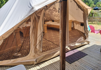 Vista esterna della tenda Sibley Apex al Campeggio Junora in Francia, con interno accogliente e terrazza in legno.