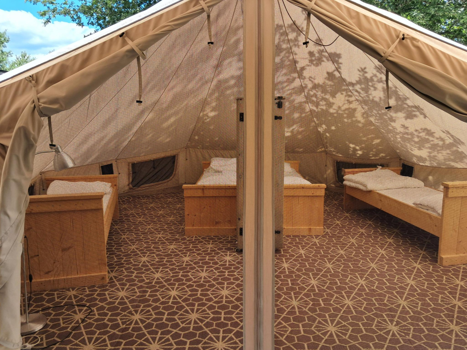 Interieur van een Sibley Apex tent met vier bedden op Campsite Junora in Frankrijk, ingericht voor gasten.