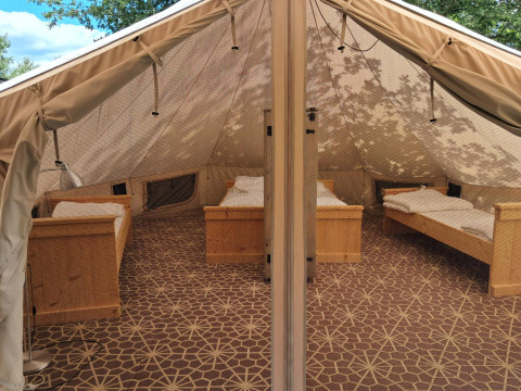 Interieur van een Sibley Apex tent met vier bedden op Campsite Junora in Frankrijk, ingericht voor gasten.