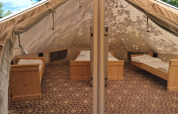 Interior of a Sibley Apex tent with four beds at Campsite Junora in France, set up for guests.