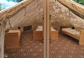 Interno di una tenda Sibley Apex con quattro letti al Campsite Junora in Francia, pronta per gli ospiti.