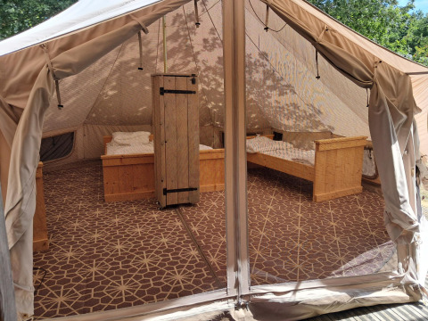 Vista interna di una tenda Sibley Apex con quattro letti in legno e tappeto al Campeggio Junora in Francia.
