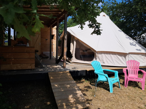 Lodge Sybley Apex tent al Campeggio Junora in Francia con terrazza in legno e sedie colorate all’esterno.