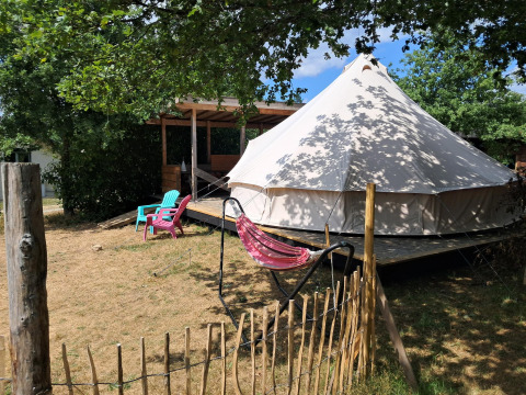 Sibley Apex tent op Campsite Junora in Frankrijk, met buitenstoelen en een hangmat onder de bomen.