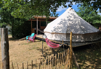 Tenda Sibley Apex al Campeggio Junora in Francia, con sedie colorate e un'amaca all'aperto sotto gli alberi.