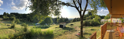 Vista panoramica su prati verdi, alberi e terrazza della tenda safari presso il Campeggio Junora in Francia