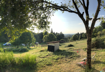 Vista panoramica su prati verdi, alberi e terrazza della tenda safari presso il Campeggio Junora in Francia