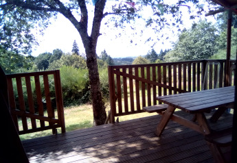Terraza de madera con mesa en la tienda safari Luxury and spacious Eco-lodge, Camping Junora, Francia.