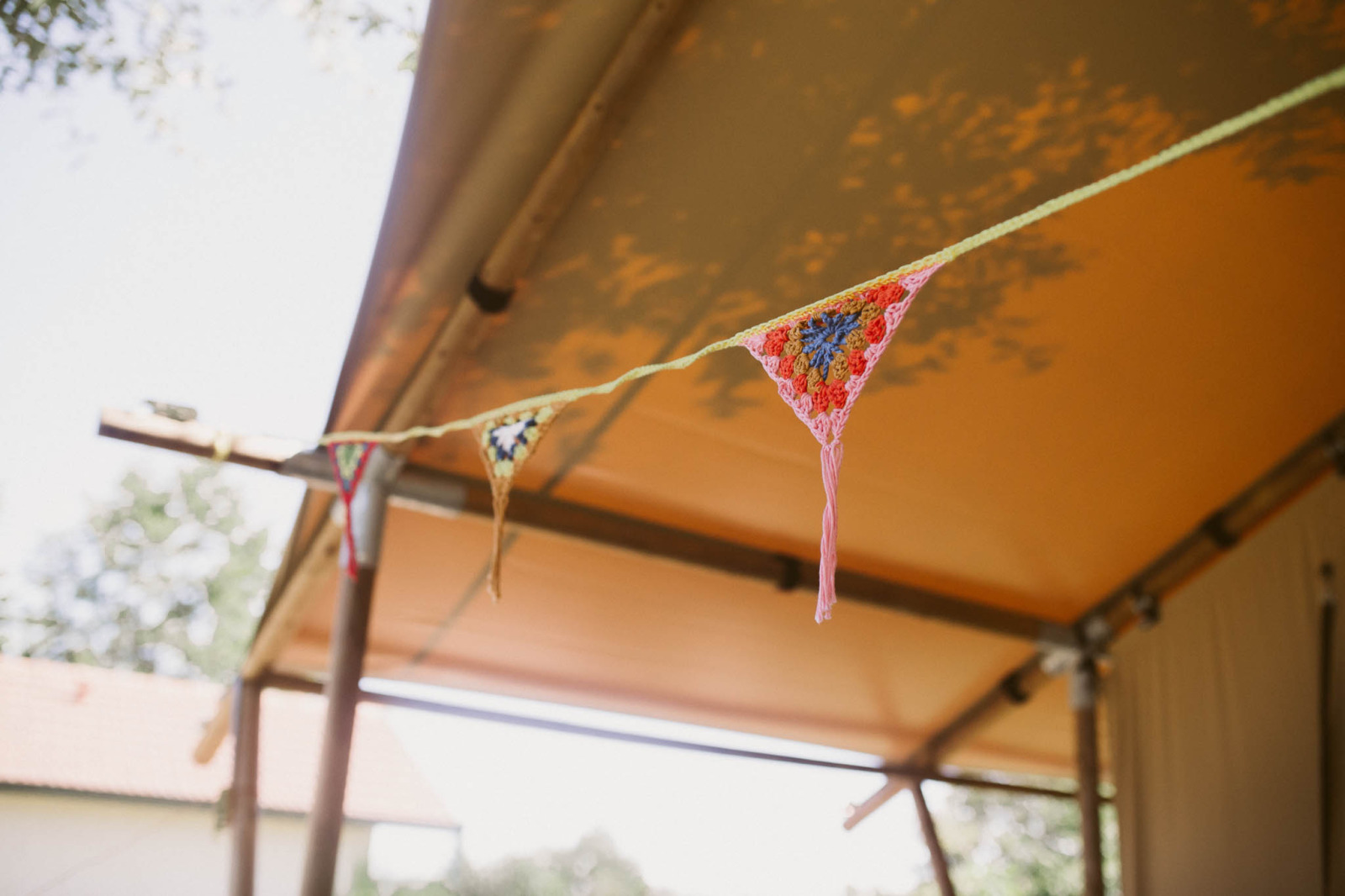 Gehaakte vlaggetjeslijn onder het tentdoek bij de luxe en ruime Eco-lodge op Camping Junora in Frankrijk.