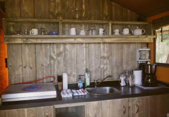 Cocina rústica completamente equipada en una tienda safari eco-lodge de lujo en el Camping Junora, Francia.
