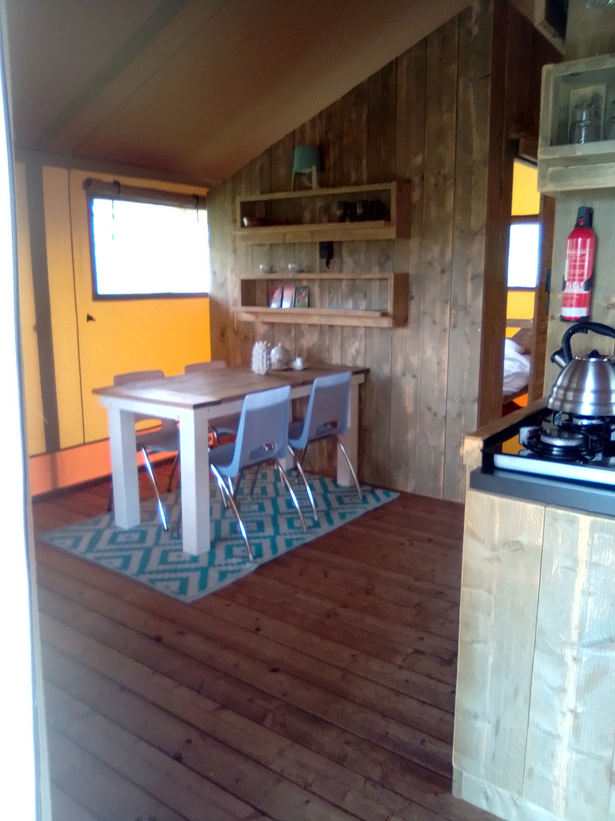 Interieur van een luxe en ruime eco-lodge safaritent op Camping Junora, Frankrijk, met houten decor.