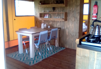 Interior de una tienda tipo safari Eco-lodge en Camping Junora, Francia, con decoración de madera.