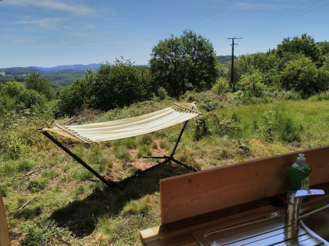Vue depuis la tente Bell XL au camping Junora en France, avec un hamac et un évier au premier plan.