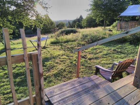 View from wooden deck at Bell XL family tent, Campsite Junora, France, over grassy field in morning light.