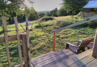 View from wooden deck at Bell XL family tent, Campsite Junora, France, over grassy field in morning light.